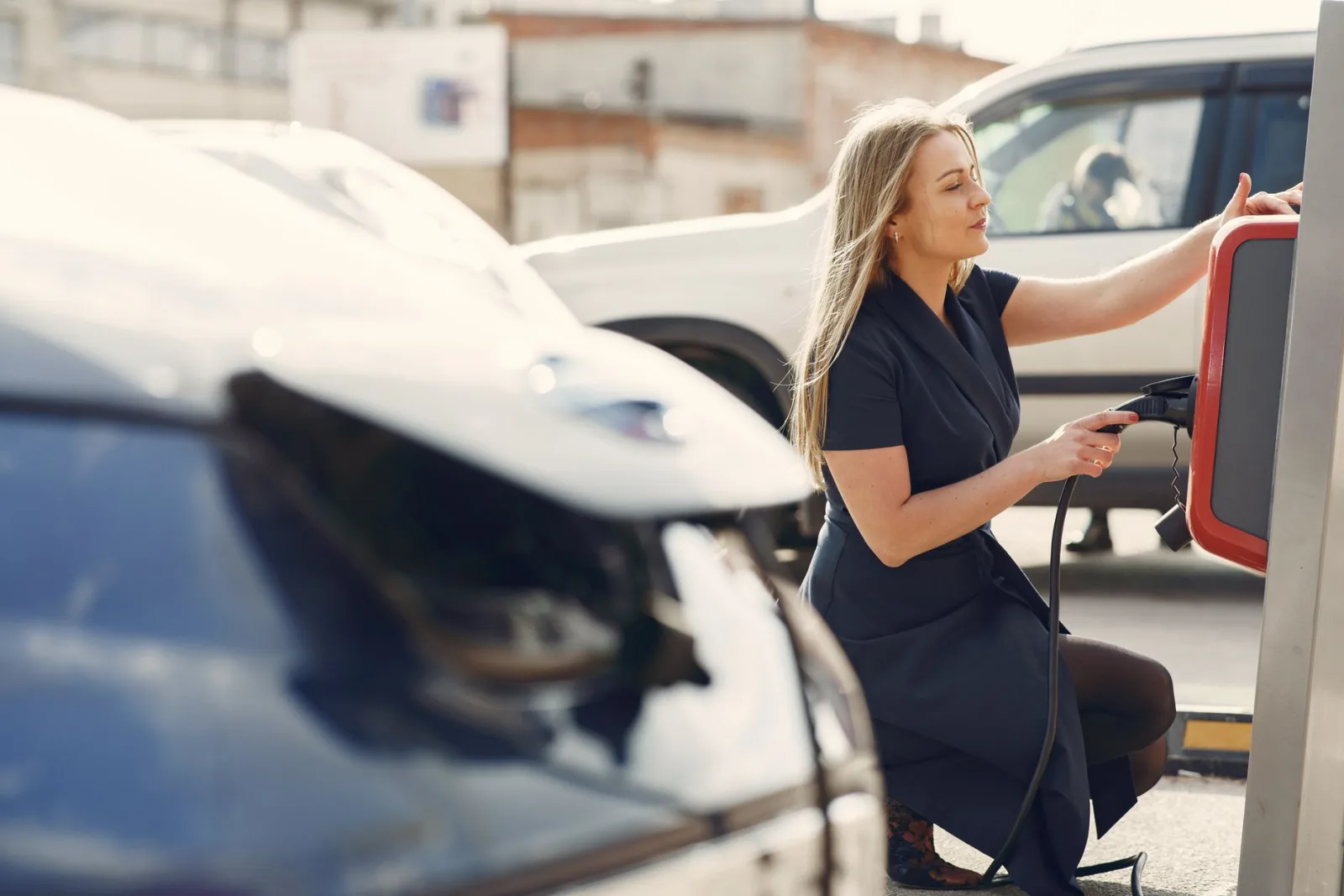 Driver plugging a charging cable into an electric car at a public street charger