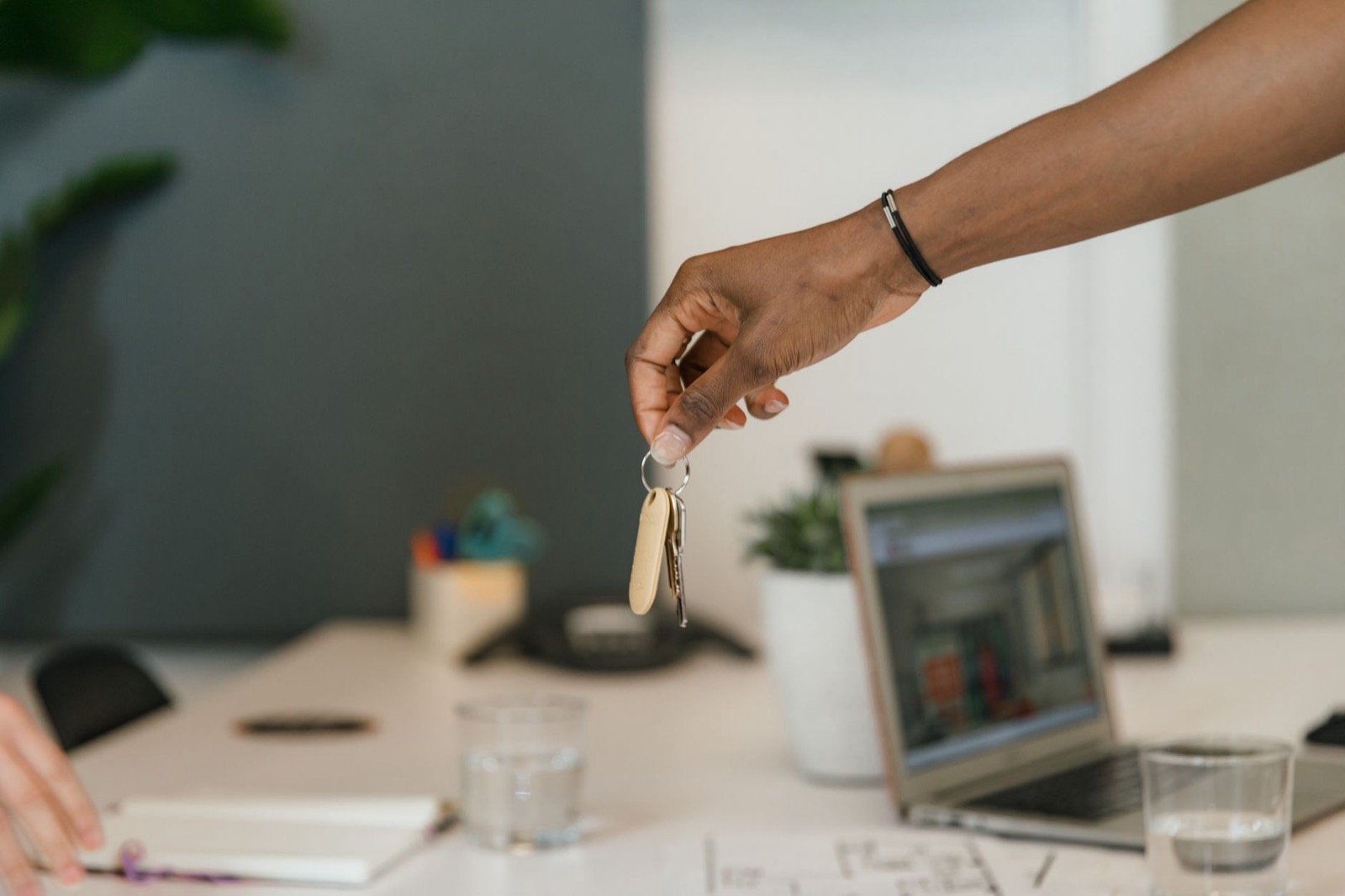 Hand holding out a bunch of keys above a desk, symbolising the transfer of ownership of a vehicle